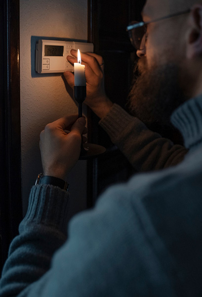 Photo d'un homme s'éclairant à la bougie suite à une panne électrique.